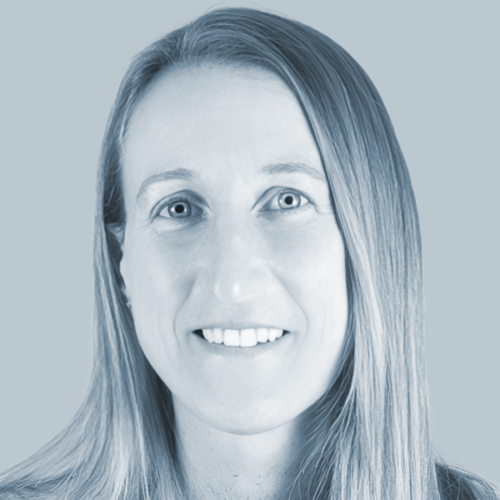 Close-up portrait of a smiling woman with long straight hair against a blue-tinted background.
