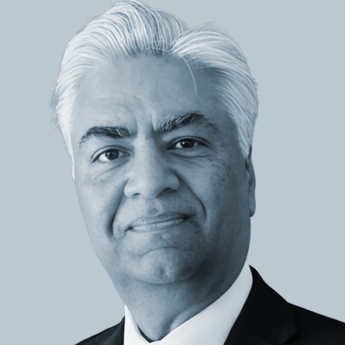 Head-and-shoulders portrait of a mature man with white hair in a dark suit and white shirt.