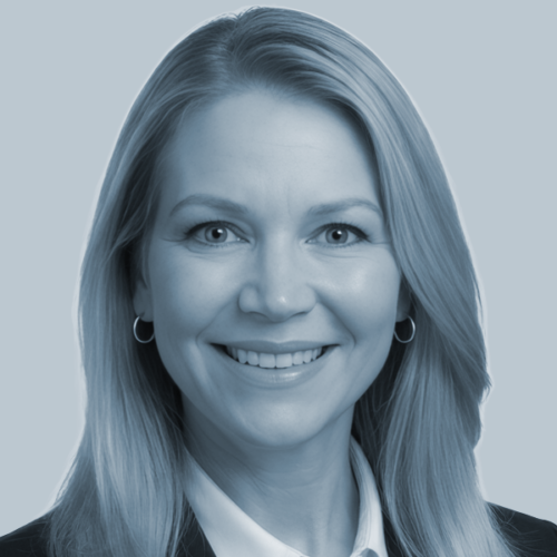 Professional headshot of a smiling woman with shoulder-length blond hair, wearing a white collared shirt and hoop earrings.